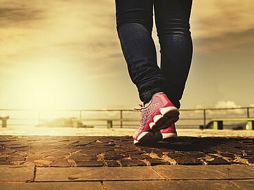 Ein Mensch in Turnschuhen läuft auf dem Asphalt.