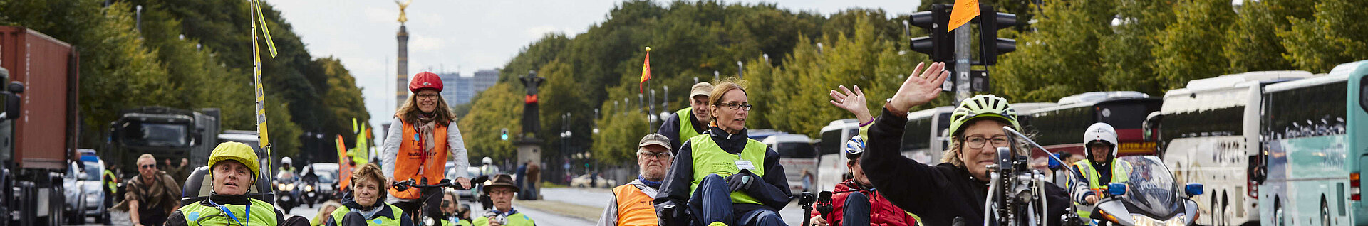 Menschen fahren mit behindertengerechten Rädern. Im Hintergrund die Siegessäule.
