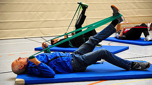 Menschen auf Sportmatten in einer Turnhalle.