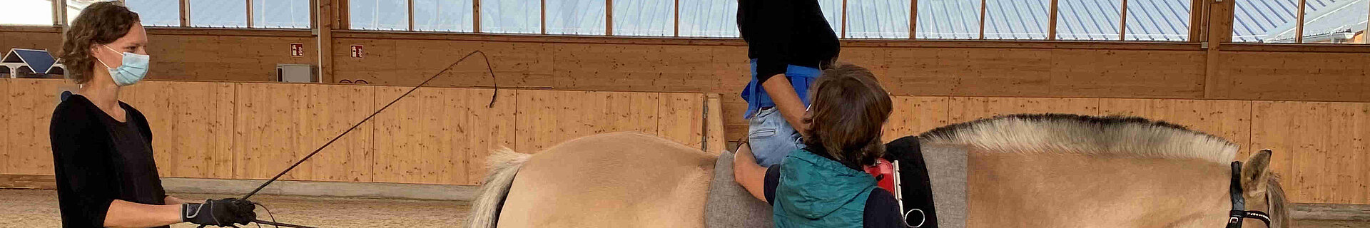 Hippotherapie (Bild: RBO – Mensch und Pferd gGmbH) Eine Person sitzt auf einem Pferd. Zwei weitere Personen führen das Pferd und stützen die auf dem Pferd sitzende Person.