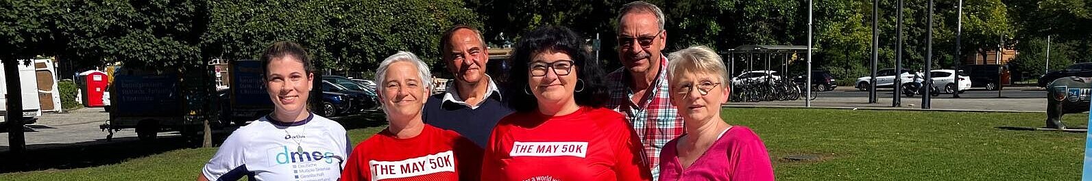 Gruppenfoto von sechs Menschen in einem Park.