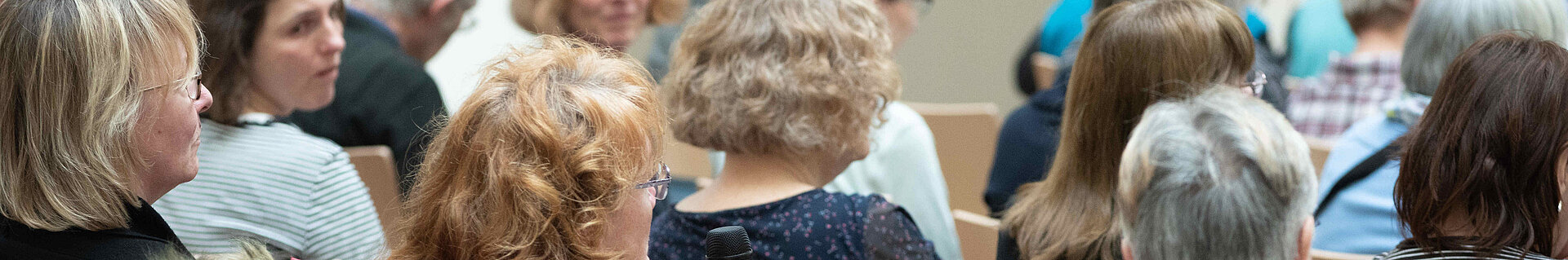 Eine Frau im Publikum spricht in ein Handmikrofon.