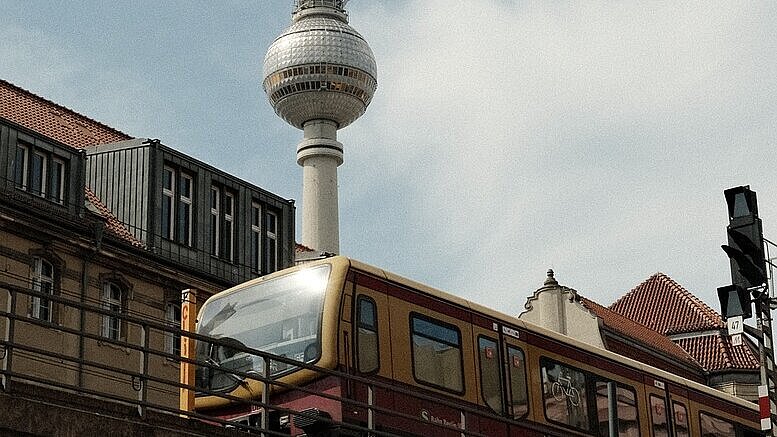 Blick auf den Berliner Fernsehturm. Davor eine S-Bahn.