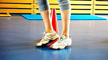 SpoKs Blick auf die Beine einer Person in einer Turnhalle.