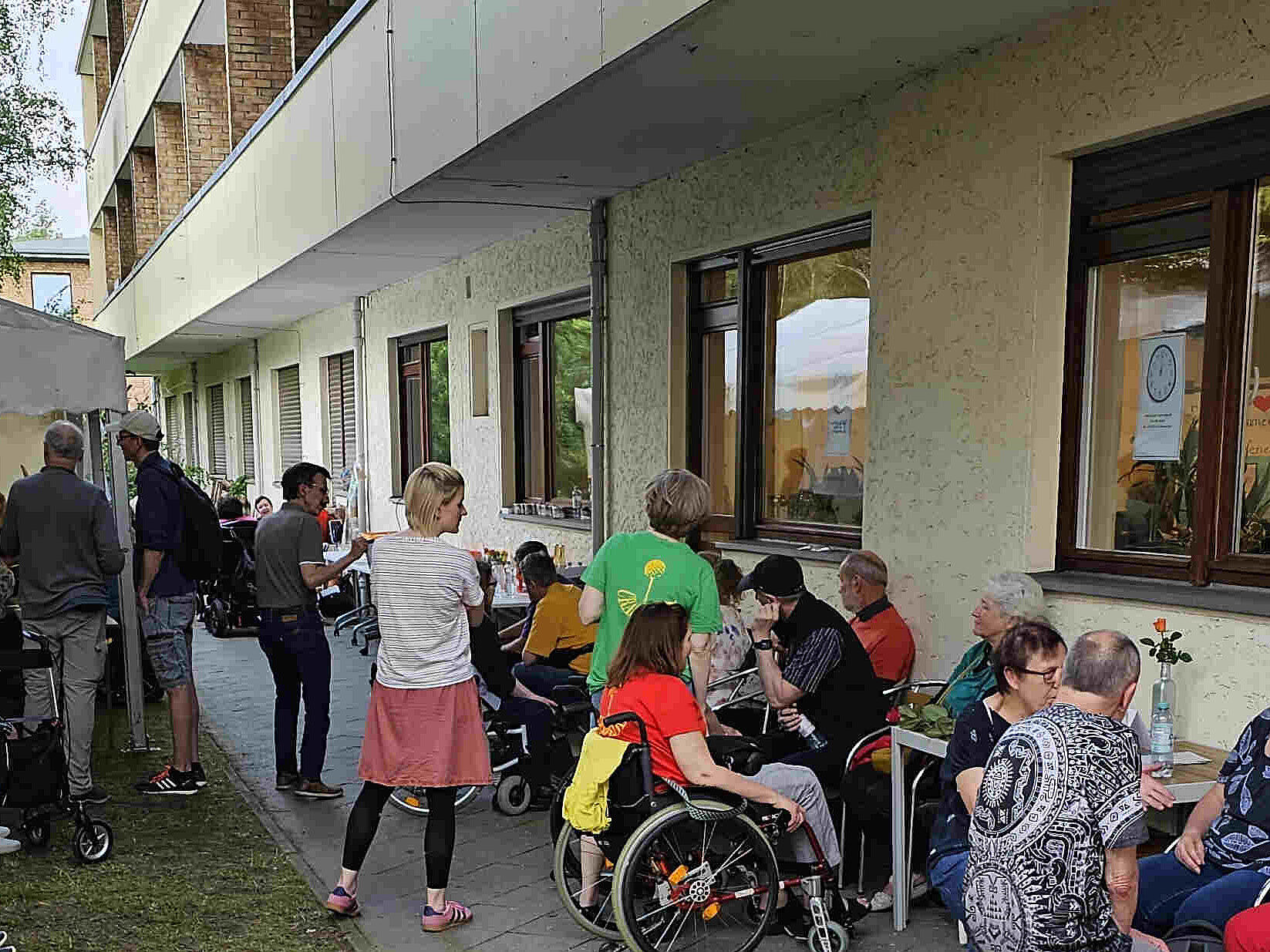 Tag der offenen Tür Menschen stehen und sitzen auf einer Rasenfläche.