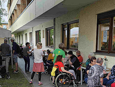 Tag der offenen Tür Menschen stehen und sitzen auf einer Rasenfläche.