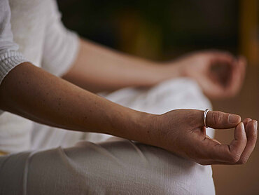 Yoga im Sitzen Eine Frau im Schneidersitz, die meditiert.