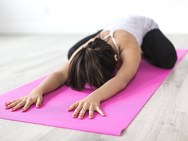 Eine Frau macht Yoga auf einer Matte.