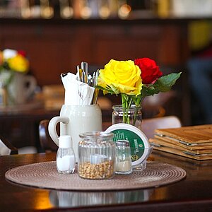 Blumen, Besteck und Zucker auf einem Café-Tisch.